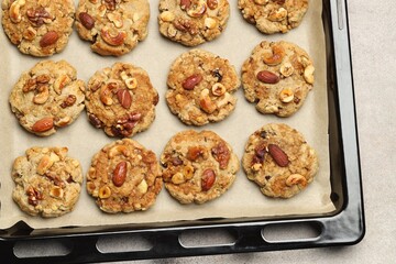 Tasty cookies with nuts in baking tray on gray table, top view
