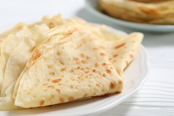 Tasty crepes on white wooden table, closeup
