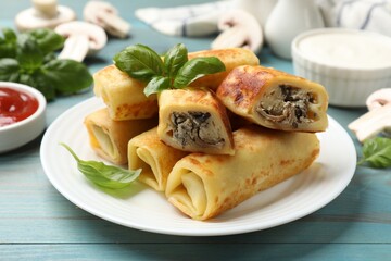 Delicious rolled crepes with mushrooms and basil on light blue wooden table, closeup