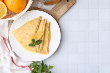 Tasty crepes Suzette and products on white tiled table, flat lay. Space for text