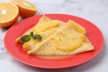 Plate with tasty crepes Suzette on white marble table, closeup