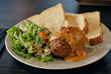 Dutch meatball with satay sauce, fresh salad, and slices of bread