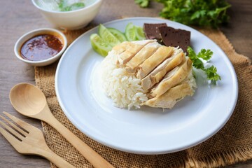 Chicken and rice with coriander and cucumber with sauce and soup in a white plate, hainanese chicken rice, thai called khao man gai, asian food, thai food