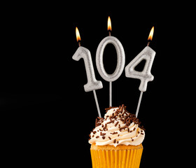 Birthday cupcake on black background - Number 104 shaped candles.