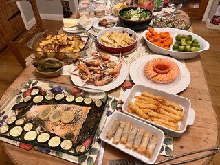 Christmas table family celebration feast cold buffet delicious fish dishes courgette lemon decorates salmon prawn rings tails langoustin spring rolls salads and vegetables with pickles cheese biscuits
