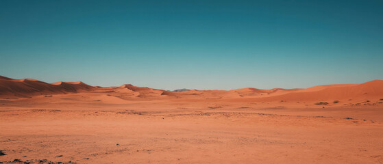 Naklejka premium Clear blue sky over vast desert landscape with gentle dunes and tranquil atmosphere
