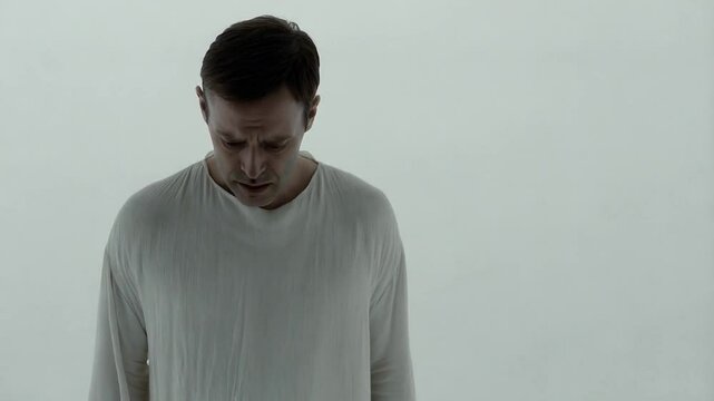 Desperate Man in White Clothing Standing in a White Limbo, Symbolizing Purgatory and Judgment