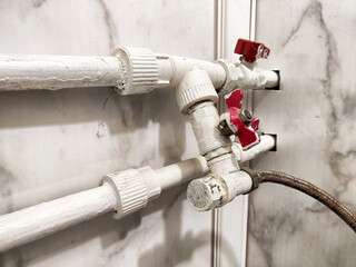 Plumbing pipes installed on a wall with valves for controlling water flow in a residential setting