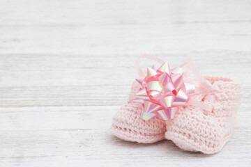 Pink baby booties with a bow on wood