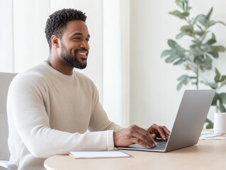 Young man taking notes while working on a laptop, sitting in a bright room with plants on the desk, concepts of e-learning, remote education, and study.