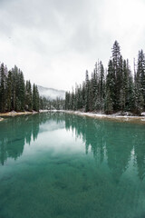 Maligne Lake in Alberta, Canada, in winter with snow covered mountains and turquoise colored water and a cloudy sky. Canada travel destination. Background