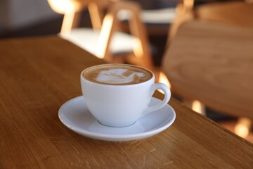 Cup of aromatic coffee on wooden table in cafe, closeup