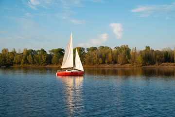 A small red boat is sailing on a lake