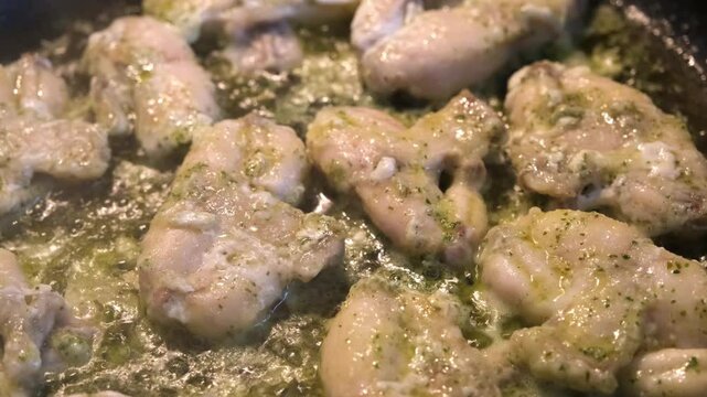 Tender frog legs simmering in rich garlic butter sauce, bubbling gently in a pan, exuding savory aromas, perfect for culinary lovers and gourmet stock.