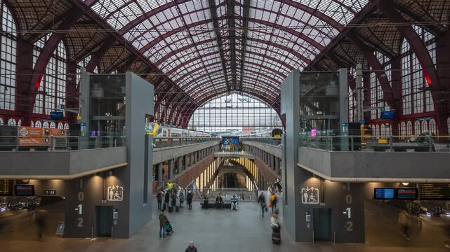 Antwerp, Belgium - December 24th 2024: Time lapse of Antwerp central train station with commuters making their way to the platforms, trains departing and arriving, motion blur to indicate movement