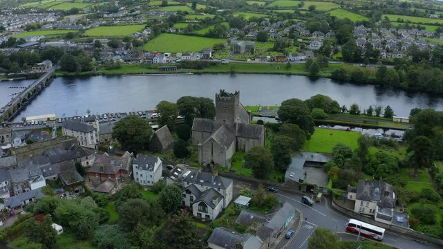 St Flannan's Cathedral, Killaloe, County Clare, Ireland, September 2021. Drone orbits counter clockwise at a high angle with the River Shannon winding through the background on an overcast day.