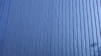 Obraz premium Corrugated metal sheet wall. Background of black corrugated steel sheets with vertical corrugations as wall of modern building with copy space with selective focus.