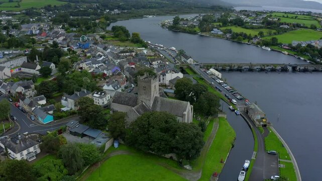 St Flannan's Cathedral, Killaloe, County Clare, Ireland, September 2021. Drone orbits counter clockwise revealing the Gothic facade on the banks of the River Shannon on an overcast rainy day.