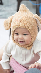 The baby is wearing a wool hat and smiling happily, the angle of the photo is tilted