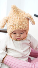 The baby is wearing a wool hat and smiling happily, the angle of the photo is tilted