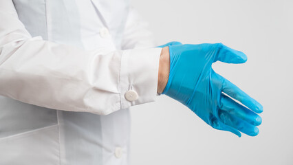 The doctor puts on latex gloves on a white background. 