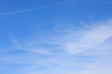 white clouds and some white streaks contrasting with the blue sky