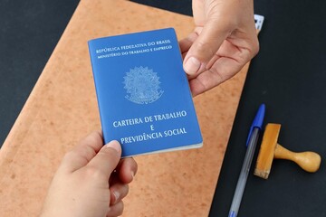Signing the Brazilian work card. Translation: Federative Republic of Brazil, Ministry of Labor.| Brazilian Work Card (Carteira de Trabalho). Formal job concept.