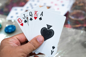 Man holding cards with royal flush but different suites showing a lucky hand in poker, rummy, teen...