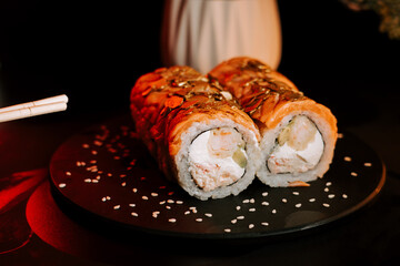 Sushi Rolls Presented on a Dark Plate Garnished With Sesame Seeds Showcase Fresh Ingredients and Culinary Artistry in a Dimly Lit Setting