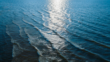 top view of Ocean blue and calm with sun rays reflection on smooth waves as textured blue background for banner template or web page design. Water calm with smooth waves.