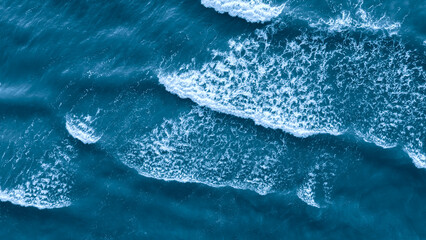 Ocean is blue and has waves as a flat textured blue background top view for web page banner template design. The waves are small and crashing on the shore. water is calm and peaceful.