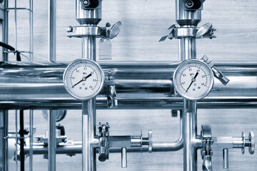 Two pressure gauges in an industrial chemical or pharmaceutical plant with shiny stainless steel...