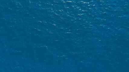 Flat lay top view of Ocean blue and calm with sun rays reflection on smooth waves as textured blue...