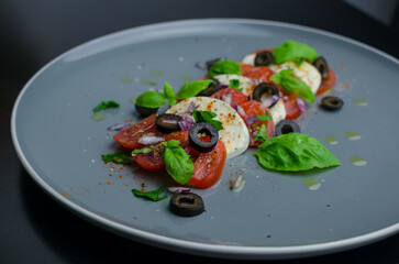 Mozzarella and tomato salad  with basil leaves  and black olives - Italian antipasti