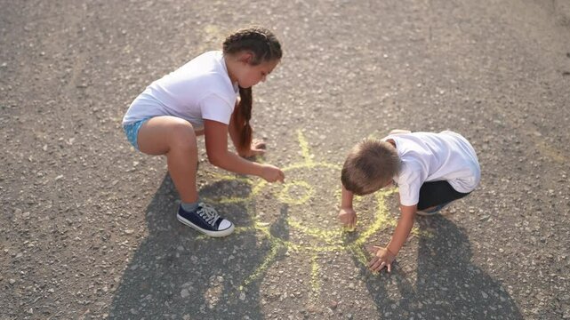 Children drawing the sun with chalk. Happy family kid dream concept. Children drawing on lifestyle the asphalt with. chalk. Children drawing the sun on asphalt with chalk.