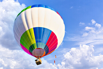 Obraz premium Colorful hot air balloon flying over blue sky with white clouds 