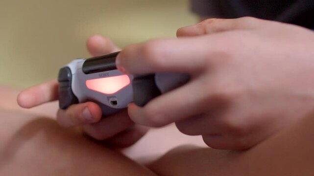 The image captures hands firmly gripping a video gaming controller that features illuminated buttons
