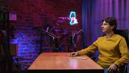 Man host sitting at the table waiting for the guest, preparing for recording interview in loft...
