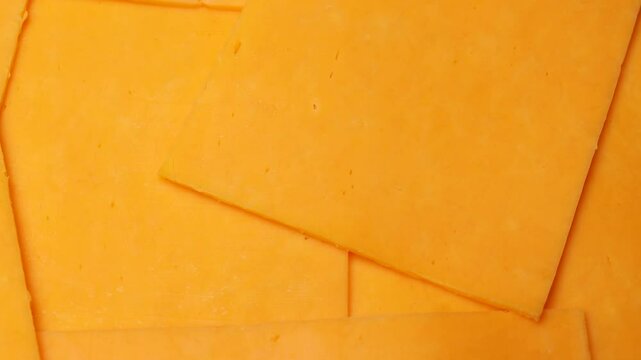 slices of yellow cheddar cheese, rotation in circle. Square slices of processed cheese for a burger, Turning.  
