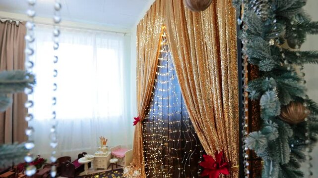 Ornaments of fir tree branches, cones, balls and beads. Approaching golden sparkling curtains with festive lights. Christmas phot zone.