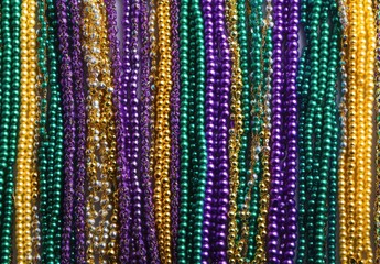 Colorful strands of decorative beads in vibrant hues of purple, green, and gold, perfect for festive celebrations and party decorations or themed events.