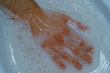 Fototapeta premium A close-up of hands being thoroughly washed under running water with soap suds forming, symbolizing personal hygiene