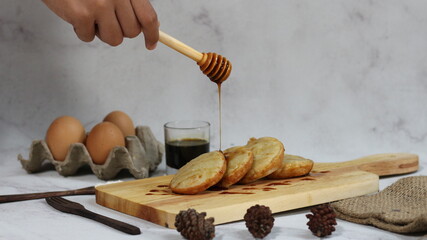 Serenading Sweetness:  Honey Drizzled Kue Ape on Wooden Board