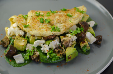 Breakfast or brunch recipe - Omelette with avocado, mushrooms, goat cheese and spinach filling, top view