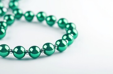 Obraz premium Elegant Green Beads Arranged Beautifully on a Soft White Background, Perfect for Jewelry Decoration, Fashion Design and Stylish Accessories Photography