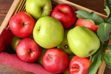 Ripe red and green apples in wooden crate on table, top view