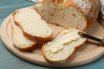Fresh bread with butter and knife on blue wooden table, closeup