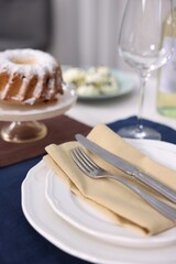 Festive table setting with dishware, cutlery, glass and dessert indoors, closeup