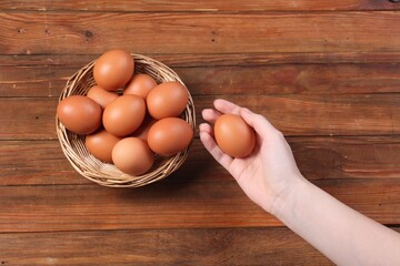 Woman with raw eggs at wooden table, top view