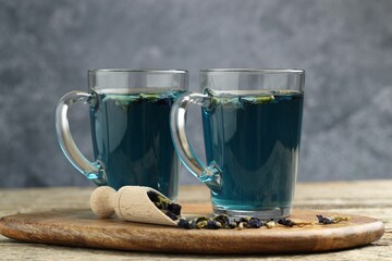 Delicious butterfly pea flower tea on wooden table against gray background